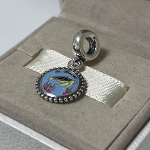 Puede incluir: Un charm de plata con un c&iacute;rculo de esmalte azul que presenta una tortuga marina amarilla y el texto "St. Maarten". El charm tiene un borde de cuentas de plata y un lazo de plata para sujetarlo a una pulsera.