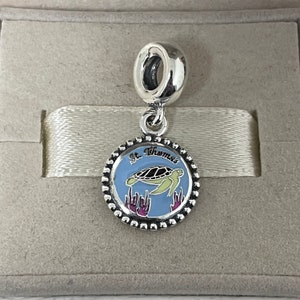Puede incluir: Encanto de plata con un c&iacute;rculo de esmalte azul que presenta una tortuga marina verde nadando en agua azul con coral morado. El c&iacute;rculo tiene un borde de cuentas y el texto "St. Thomas" en letras negras.