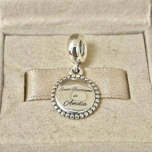 May include: Silver charm with a round disc featuring the inscription "Santo Battesimo di Amelia".
