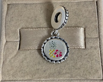 May include: Silver charm with a pineapple and hibiscus flower design. The charm is in a small box with a brown velvet lining.