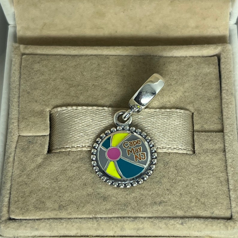 May include: Silver charm with a colorful beach ball design and the text "Cape May NJ".
