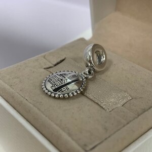 Puede incluir: Un charm de plata con una imagen detallada de un edificio, posiblemente un monumento europeo, con una cuenta redonda de plata en la parte superior.