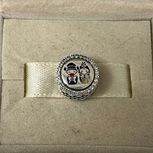May include: Silver charm with a white background and a colorful image of a couple in traditional Chinese clothing. The charm is surrounded by a circle of clear cubic zirconia stones.