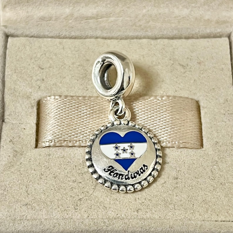 Pu&ograve; includere: Ciondolo d'argento con un cuore blu e bianco che presenta la bandiera honduregna e la parola "Honduras" in lettere bianche.