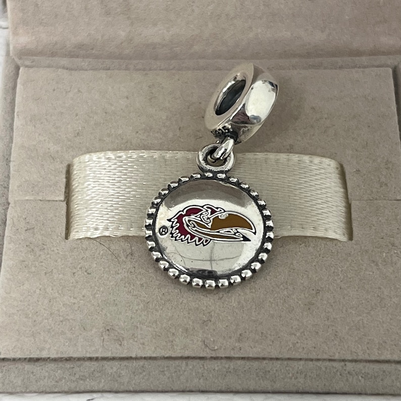 Op de afbeelding: Zilveren bedel met een rood, geel en wit University of Arkansas Razorback logo op een ronde schijf met een parelrand.