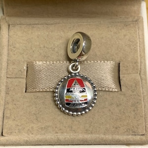 May include: Silver charm with a red, yellow, and black enamel design. The charm features the text "SOUTHERNMOST POINT" and "CONTINENTAL USA".