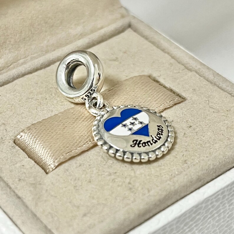 Pu&ograve; includere: Ciondolo d'argento con un ciondolo a forma di cuore blu e bianco con la bandiera dell'Honduras e la parola "Honduras" in lettere nere.