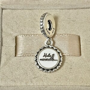 Puede incluir: Encanto de plata con un c&iacute;rculo de esmalte blanco que dice "Make it memorable..." y un borde en forma de coraz&oacute;n. La parte posterior del encanto tiene la inscripci&oacute;n "S925 ALE".