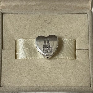 Puede incluir: Encanto de plata en forma de corazón con una imagen en blanco y negro de la Catedral de Colonia.