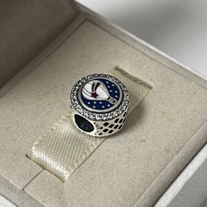 May include: A silver charm with a blue and white enamel hot air balloon design. The balloon has red and white stars and the charm is surrounded by clear cubic zirconia stones.