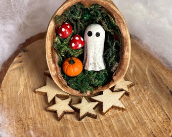Walnut shell with black-eyed ghost on a bed of moss with pumpkin and toadstool. Quirky Halloween decoration.