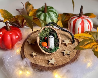 Walnut shell with black-eyed ghost on a bed of moss with pumpkin and toadstool. Quirky Halloween decoration.