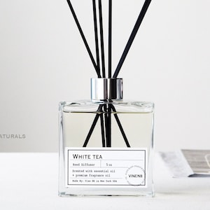 Peut inclure: Un diffuseur de roseaux en verre clair et carré avec des roseaux noirs. L'étiquette indique "White Tea" et "5 oz". Le diffuseur est parfumé à l'huile essentielle et à l'huile parfumée de qualité supérieure. Produit de VinenB Naturals.