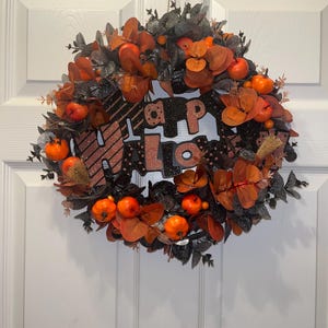Black and orange Halloween wreath with pumpkins and sign for front door