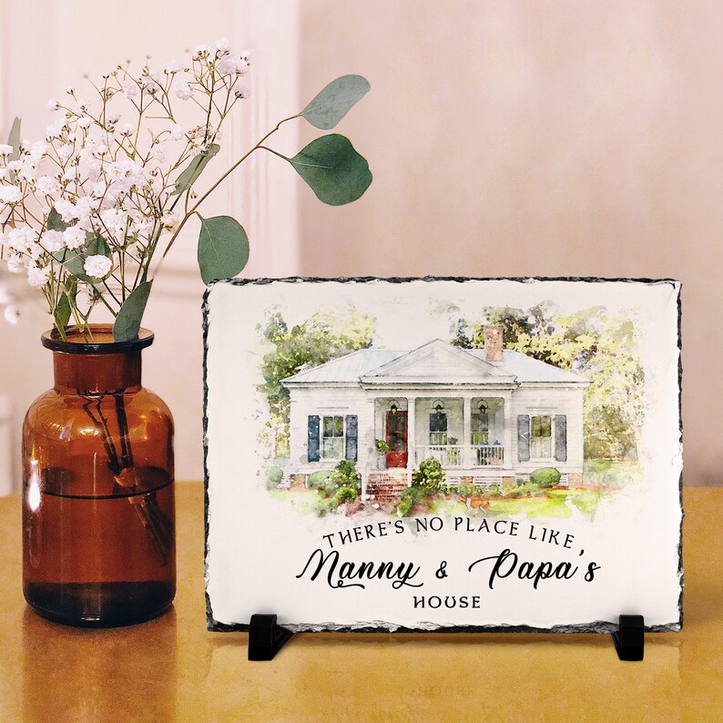 May include: A watercolour painting of a white house with a red door and a porch. The painting is on a slate plaque with the text "There's no place like Manny & Papa's House".