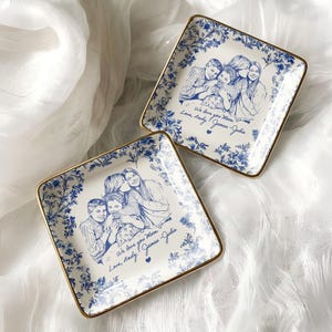 May include: Two square porcelain dishes with a blue floral border and gold trim. Each dish features a family portrait in blue ink with the handwritten text "We love you Mom, Love, Andy, James, Julia."