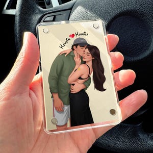 May include: A clear acrylic photo block featuring an illustration of a couple embracing and kissing. The man wears a green shirt, shorts, and a cap. The woman wears a black dress. The names "Kevin" and "Kamila" are written above the couple.