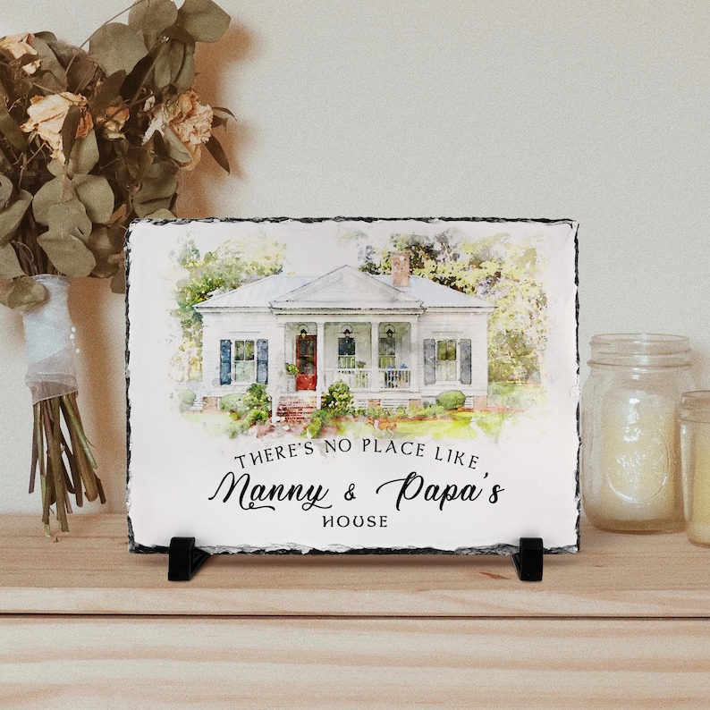 May include: A watercolour painting of a white house with a porch and green trees. The house is on a slate plaque with the text "There's no place like Nanny & Papa's House".