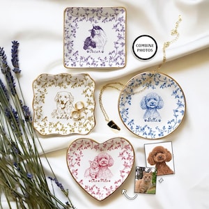 May include: A collection of personalized ceramic trinket dishes with gold rims, featuring pet portraits. The dishes are square, round, and heart-shaped, adorned with floral patterns and pet names like "Oscar," "Lily," and "Bella." The image includes a necklace and two pet photos.