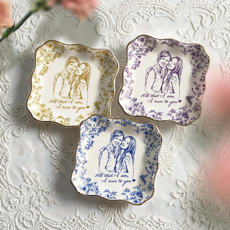 May include: Three decorative square plates with scalloped edges. Each plate features a couple's portrait and the text "All that I am, I owe to you." The plates have floral borders in gold, purple, and blue, with gold rims.