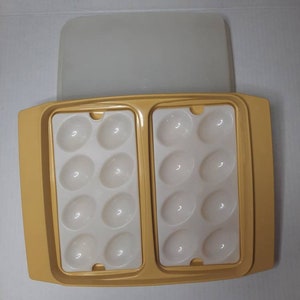 May include: A yellow plastic egg holder with a clear lid. The holder has two sections, each with six egg-shaped compartments.