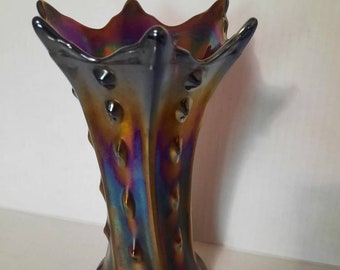 May include: A iridescent purple, blue, and gold glass vase with a starburst design and a textured surface.