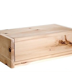 May include: A wooden bread box with a sliding lid. The box is made of light wood with a natural finish.