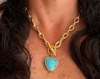 May include: A gold chain necklace with a turquoise heart pendant. The chain is a thick, chunky style with a toggle clasp.
