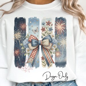 May include: White sweatshirt with a patriotic design. Features vertical stripes with fireworks, flowers, and a bow. The bow has a red and white checkered pattern. The text "Design Only" is written in cursive.