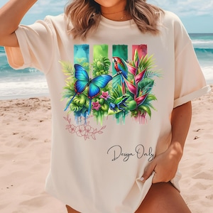 May include: Cream-colored t-shirt featuring a vibrant tropical design. The graphic includes a blue butterfly, a parrot, a frog, and lush foliage. The words "Design Only" are written in cursive.