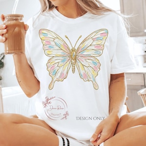 May include: White t-shirt featuring a large butterfly design with pastel pink, blue, and yellow sections outlined in gold. The text "DESIGN ONLY" is printed on the shirt. The shirt is a casual style.