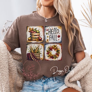 May include: Brown t-shirt featuring four square fall-themed designs. The designs include a wooden crate with pumpkins and apples, the text "Hello Fall", corn and a plaid blanket, and a fall wreath. The shirt has a relaxed fit.