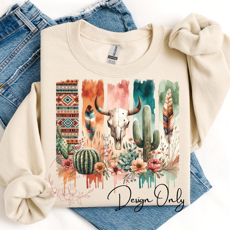 May include: A beige sweatshirt with a colorful design featuring a skull, cactus, feathers, and geometric patterns. The design has a watercolor effect and the text "Design Only" is printed on the bottom.