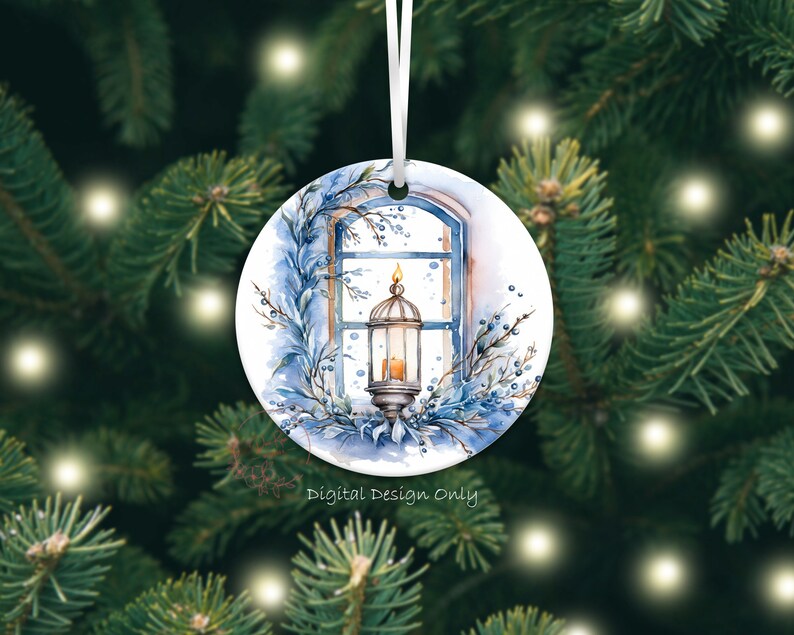 K&ouml;nnte beinhalten: Runder Weihnachtsschmuck mit einer Aquarellillustration einer Laterne in einem Fenster, umgeben von blauem Laub. Der Schmuck hat ein wei&szlig;es Band zum Aufh&auml;ngen. Der Text auf dem Ornament lautet "Digital Design Only".