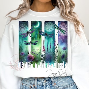 May include: A white sweatshirt featuring a watercolour design of dragonflies, flowers, and a crescent moon. The design is in shades of green, blue, and purple. The text "Design Only" is printed on the bottom of the sweatshirt.