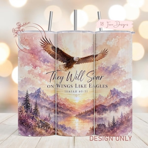 May include: A cylindrical tumbler featuring a watercolor-style landscape with mountains, a lake, and a sunset. An eagle is depicted in flight above the text "They Will Soar ON WINGS LIKE EAGLES ISAIAH 40:31". The design includes a metal straw.