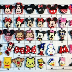 May include: A set of 40 colorful cartoon character shoe charms featuring Disney characters like Mickey Mouse, Minnie Mouse, Donald Duck, Goofy, and others. The charms are made of a durable, high-quality material and are perfect for adding a touch of personality to your shoes.