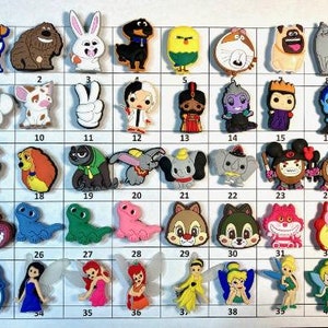 May include: A set of 40 colorful cartoon character shoe charms. The charms are made of rubber and feature characters from popular animated films. The charms are arranged in a grid pattern on a white background.