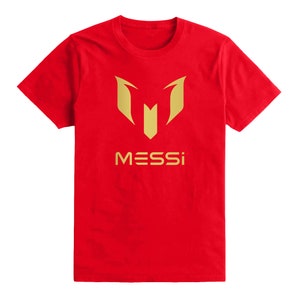 Op de afbeelding: Rood T-shirt met een gouden logo van een gestileerde "M" en het woord "MESSI" eronder.