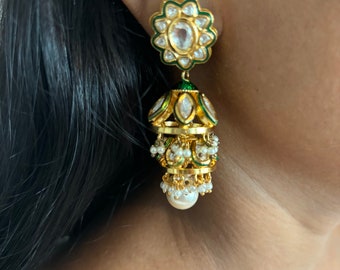 May include: Gold earrings with green enamel and white stones. The earrings have a dangling design with a pearl at the bottom.