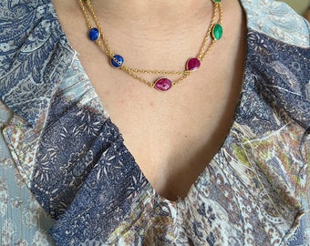 May include: A gold chain necklace with oval-shaped gemstones in shades of green, blue, and pink.