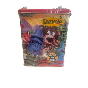 May include: A Crayola crayon tin featuring a forest scene with cartoon animals and a smiling blue crayon. The tin includes the text "Includes 24 select crayons". The tin is red and yellow.