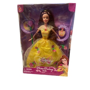 May include: A Disney Flutter Fantasy Belle doll in a clear plastic package. The doll wears a yellow gown with red rose accents. The packaging includes the Disney logo and the words "Flutter Fantasy Belle".