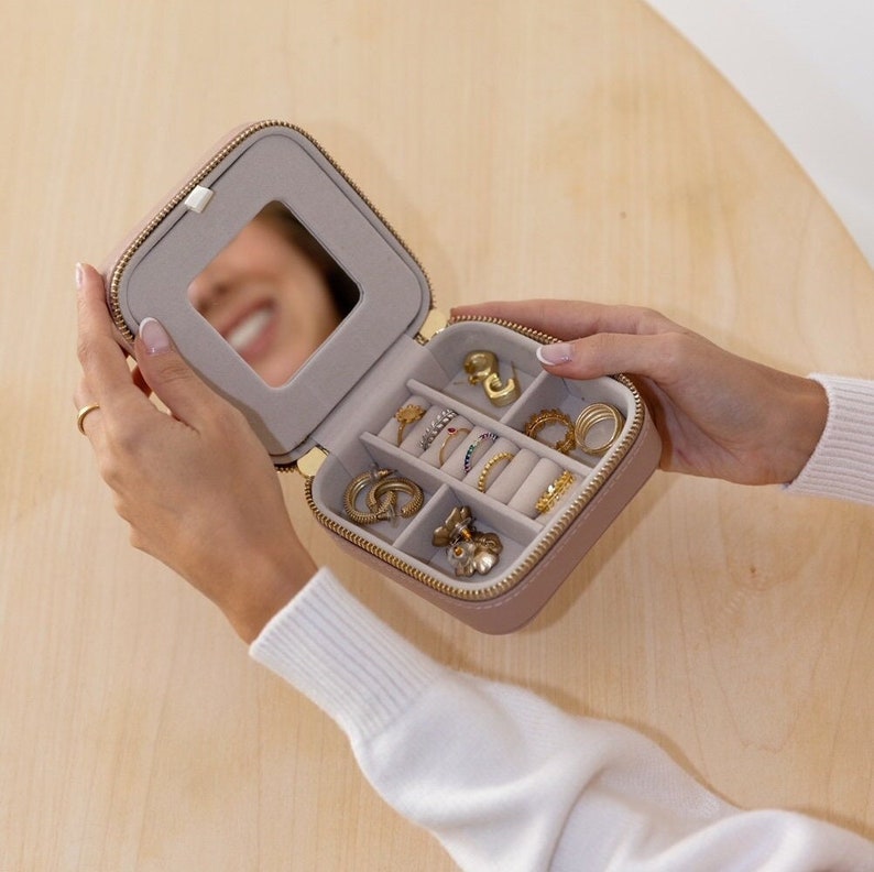May include: A light pink velvet jewellery box with a mirror and multiple compartments for storing rings, earrings, and other jewellery.