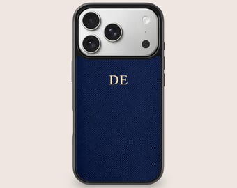 May include: A navy blue phone case with a textured finish and a black border. The case features a silver camera module and the gold letters "DE" centered on the front. The case is designed for a smartphone.