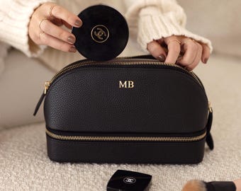 May include: Black leather travel makeup bag with two zippers and gold hardware. The bag has the initials "MB" embossed on the front.
