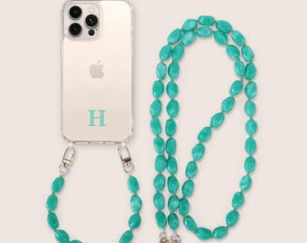 May include: A clear phone case with the letter "H" in a teal color, attached to a teal beaded phone strap. The strap is made of oval-shaped beads and silver-colored metal clasps.