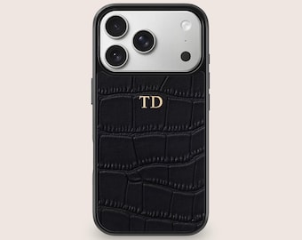May include: Black phone case with a textured, crocodile-like pattern. The case has a black frame and a silver camera section. Gold letters "TD" are centered on the case.