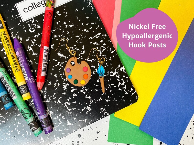 May include: A pair of earrings featuring a paintbrush and a paint palette. The paint palette is brown with colorful paint dots. The earrings are nickel free and hypoallergenic.