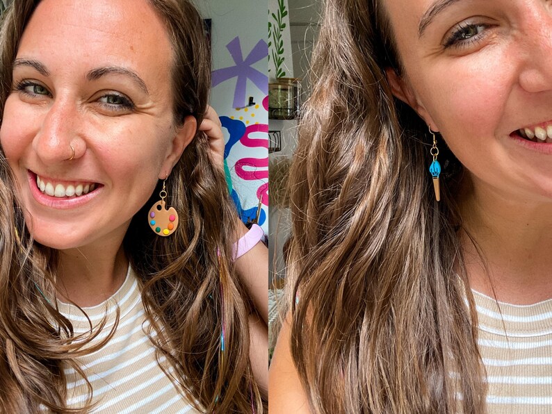 May include: A woman wearing a pair of earrings. One earring is a brown and white paint palette with colorful paint dots. The other earring is a blue and gold ice cream cone.